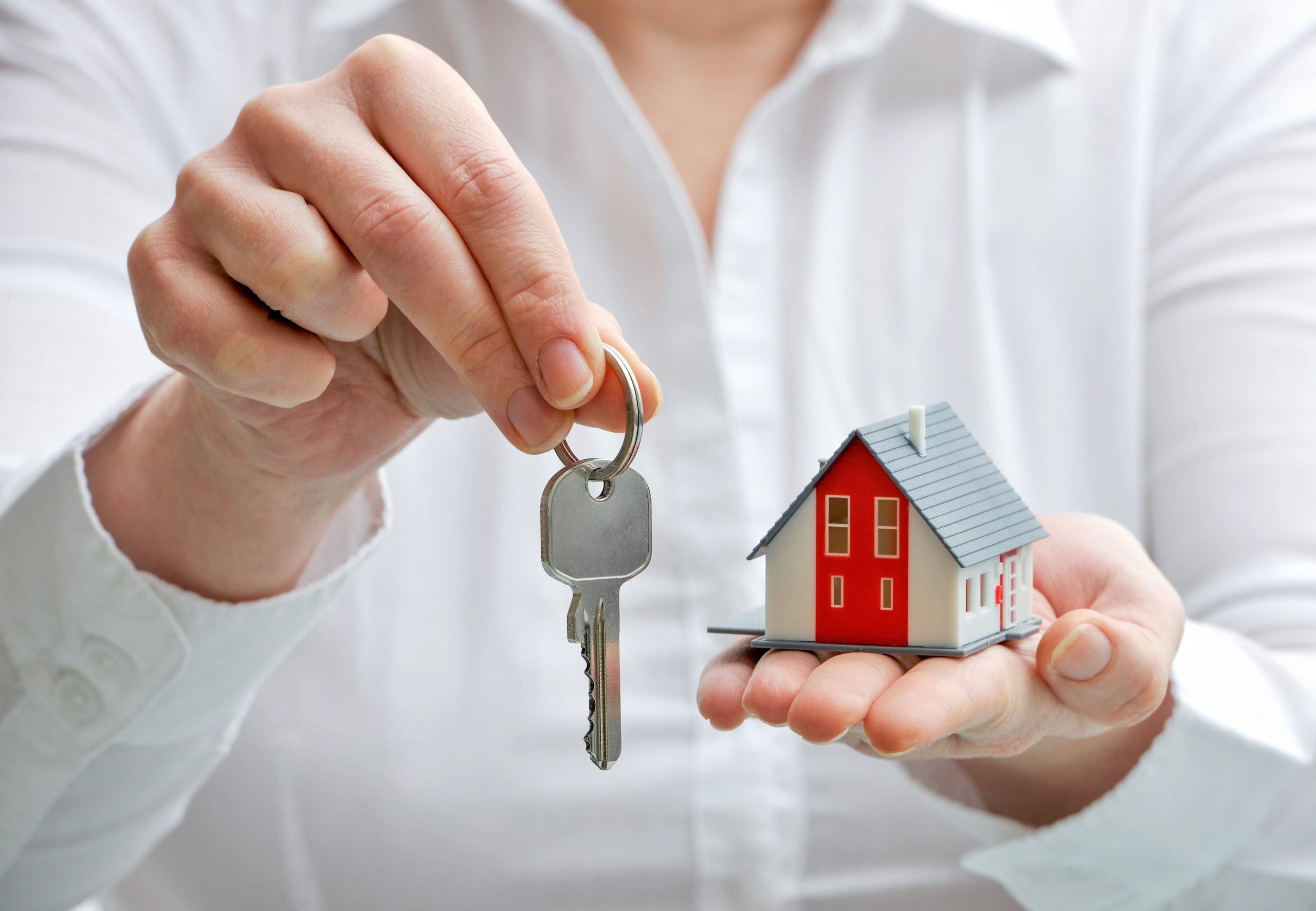 Woman holding keys and small red house